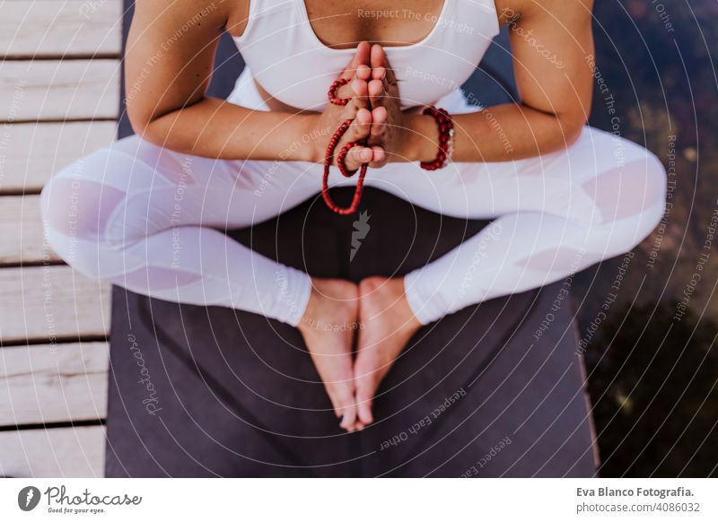 close up view of young beautiful asian woman doing yoga in a park. Sitting on the bridge with praying hands position and using Mala necklace. Yoga and healthy lifestyle concept
