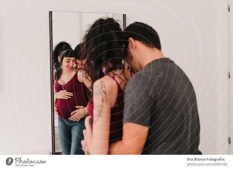 young couple at home hugging. Happy Pregnant woman. Reflection on mirror parents mobile phone smart phone pregnant picture camera smile happy portrait parenting