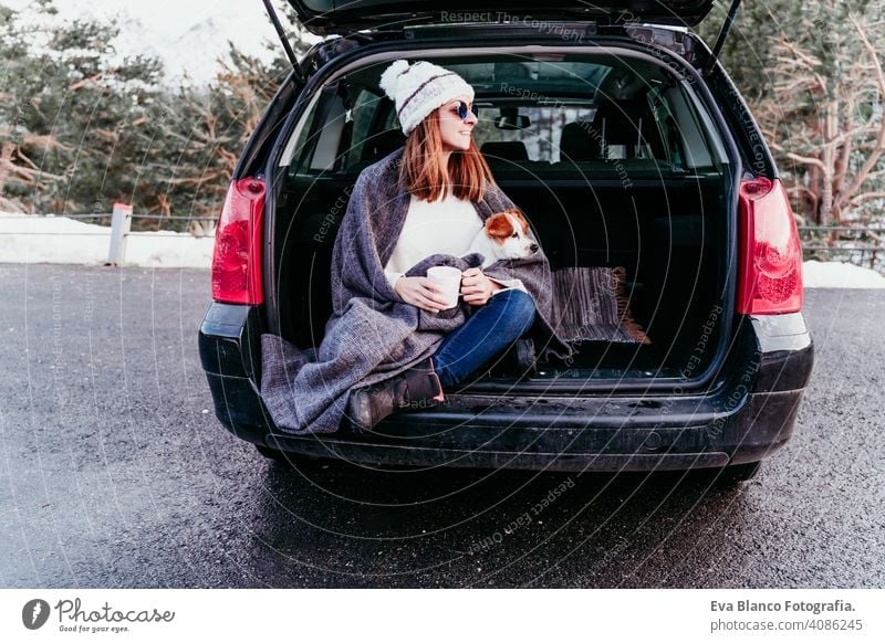 woman and cute jack russell dog enjoying outdoors at the mountain into the car. Travel concept. winter season snow travel lifestyle wanderlust traveling fun