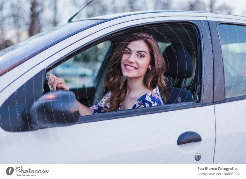 Young woman driving a car in the city. Portrait of a beautiful woman in a car, looking out of the window and smiling. Travel and vacations concepts interior