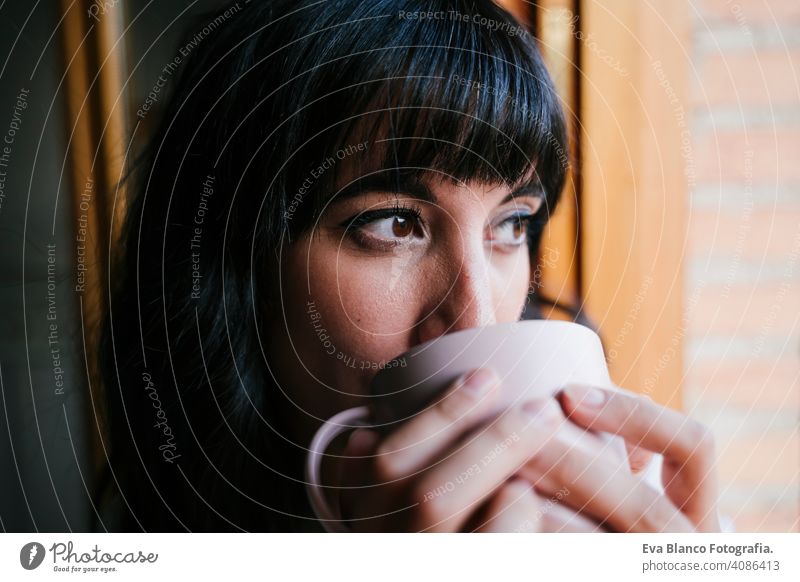 young caucasian woman at home by the window having a cup of coffee or tea. Morning and relax concept. Lifestyle indoors girl comfortable house hotel mug modern
