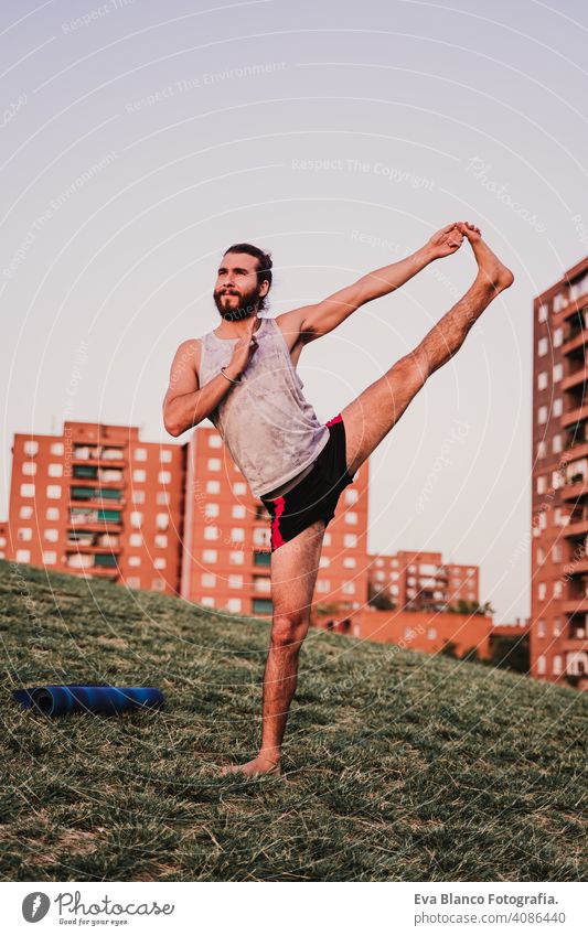 young man in a park practicing yoga sport. city background. healthy lifestyle. sunset mat sport clothes caucasian boy backpack practice concentration position