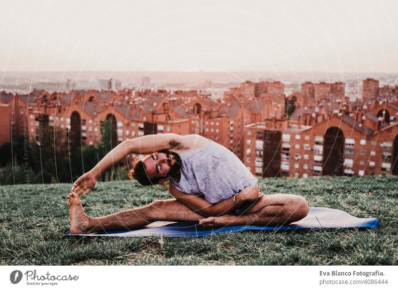 young man in a park practicing yoga sport. city background. healthy lifestyle. sunset mat sport clothes caucasian boy backpack practice concentration position