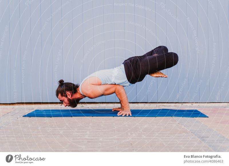 man in the city practicing yoga sport. blue background. healthy lifestyle outdoors muscular young handsome hispanic caucasian sportswear urban concentration