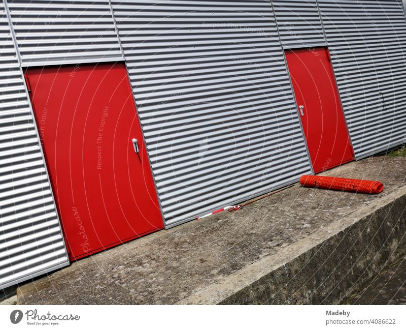 Bright red steel doors in the shimmering silver corrugated metal façade of a modern aircraft hangar at the glider airfield in Oerlinghausen near Bielefeld on Hermannsweg in the Teutoburg Forest in East Westphalia-Lippe
