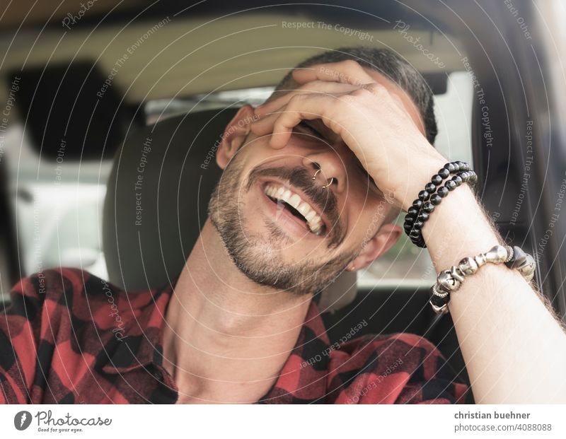 young man sitting in car laughing portrait Man 30 years Hand Bangle Teeth driver's seat happy Positive Sun Fashion vacation holilday relaxed likeable