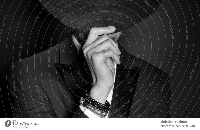 portrait of a young man with hat and arm jewellery 30 years Hand Trickle Hat Mystic Fingers hands Advertising Bangle hat brim arm joint Dark Noble