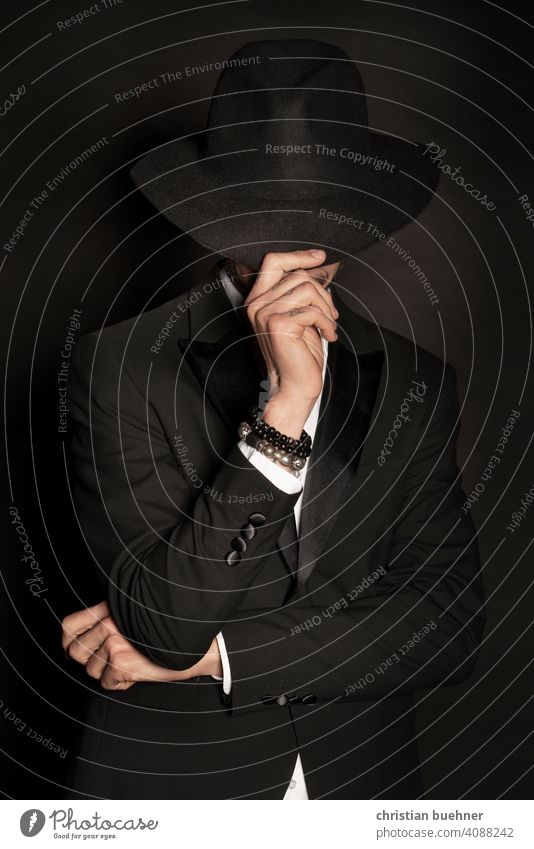 portrait of a young man with hat and arm jewellery 30 years Hand Trickle Hat Mystic Fingers hands Advertising Bangle hat brim arm joint Dark Noble