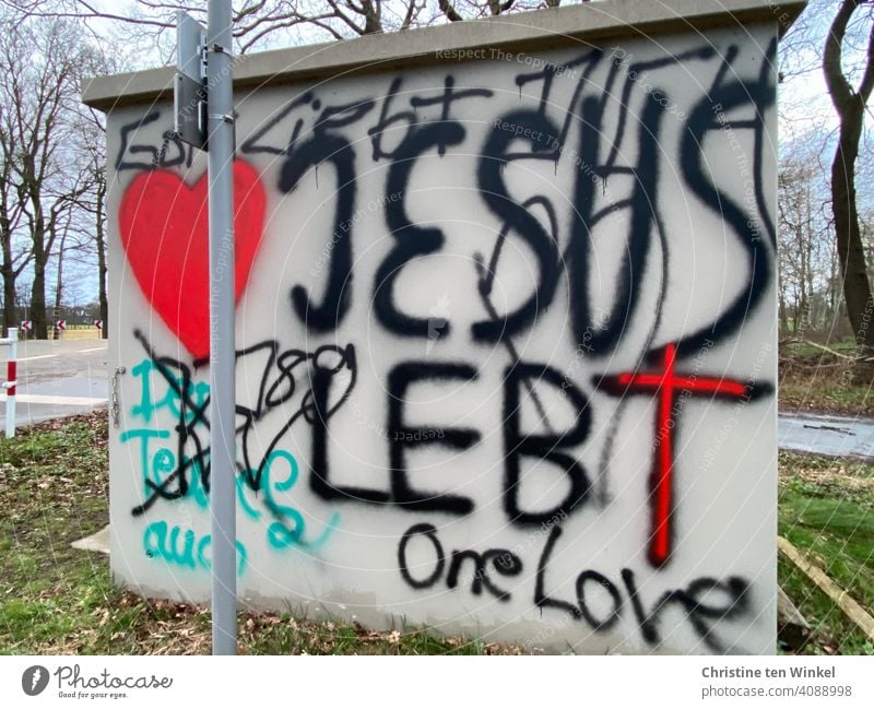 Graffiti on a transformer house...  Jesus lives, One Love, God loves you, The devil too... Heart and cross in red Devil Jesus Christ Symbols and metaphors Daub