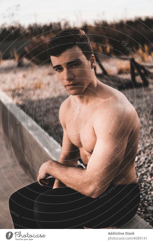 Strong male near concrete wall man fitness leaning break training city street young shirtless muscular athlete sport lifestyle cement building guy healthy