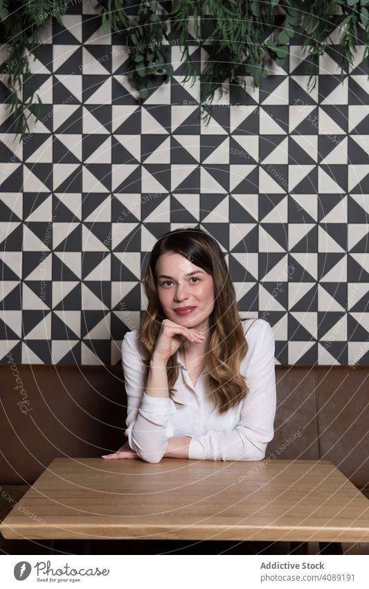 Young woman sitting at cafe portrait smiling young friendly approachable stylish looking at camera aroma lifestyle leisure rest relax trendy casual glad