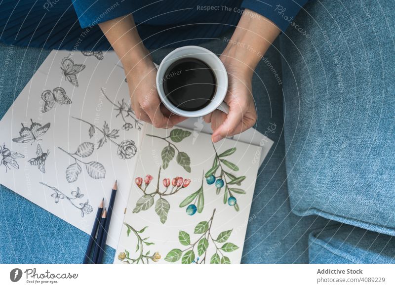 Young anonymous woman with coffee looking album with pictures painter work art cup artist workplace creativity craft brunette leisure design artwork