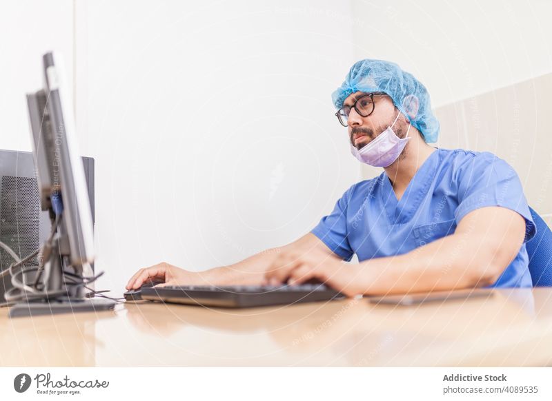 male Surgery on computer working before surgery adult hospital medical using surgeon caucasian doctor medicine office uniform coat staff scrubs day sitting