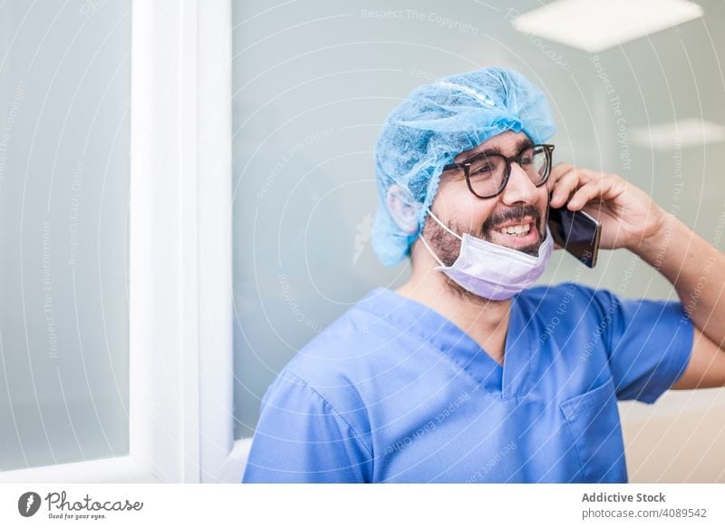 male Surgery staff using his smartphone job posture weary indoors hat wall hospital operating room professional hallway white copy space doctor corridor relax