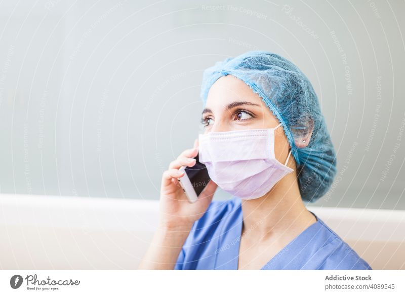 Female Surgery using her smartphone in a hospital job posture weary indoors hat wall operating room professional hallway white copy space doctor corridor relax