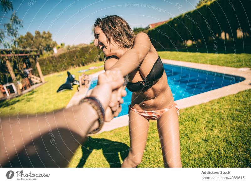 Woman holding of anonymous man woman follow me pool playful cheerful summer vacations carefree couple youth together fun laughing playing recreation tropical