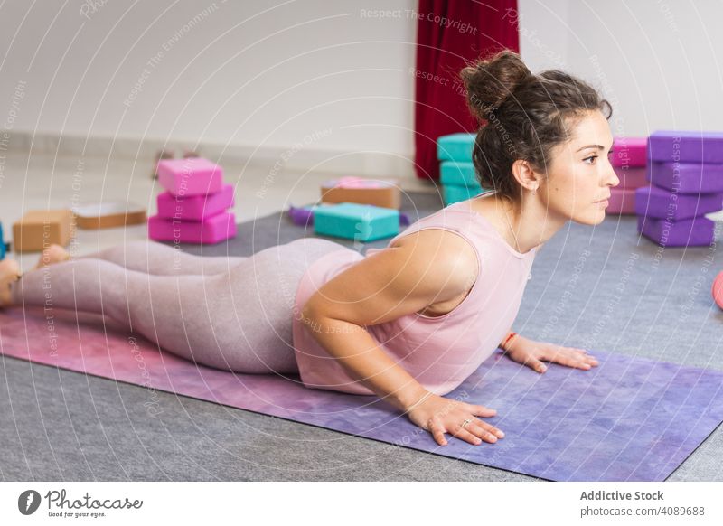 Young attractive woman practicing yoga indoors young flexible sportive concentrated pose lying sportswear brunette relaxation meditation fitness mat healthy