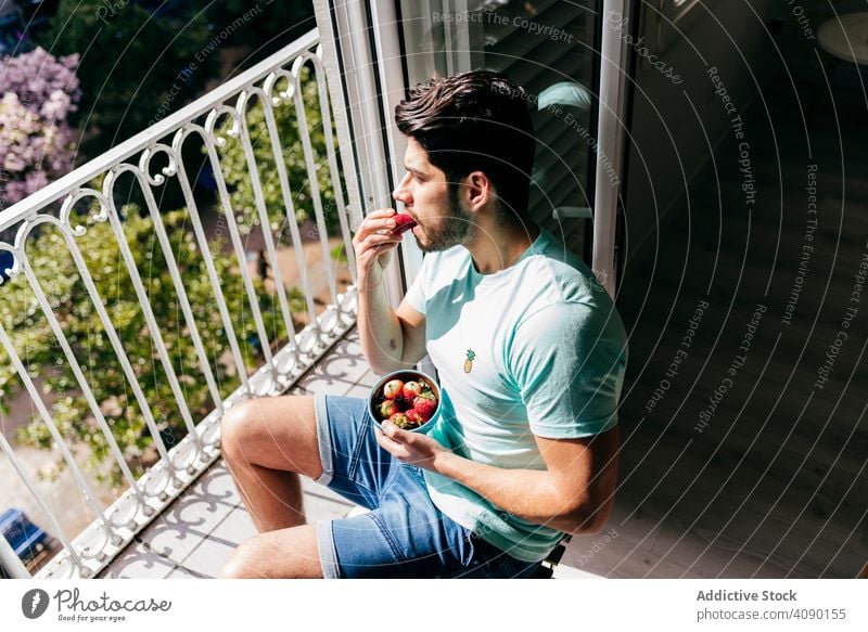 Young happy sexy male eating strawberry near terrace man bowl underwear balcony young joy cheerful handsome successful cool naked hot brutal hunk macho muscular