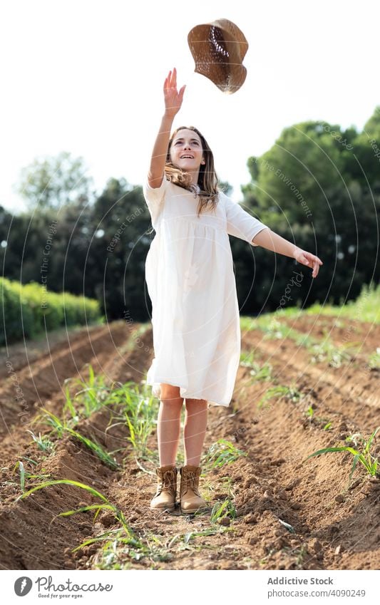 Cheerful teenager throwing hat in field fun sunny daytime catalonia spain anoia girl nature summer young female happy cheerful smiling glad joy dress farm