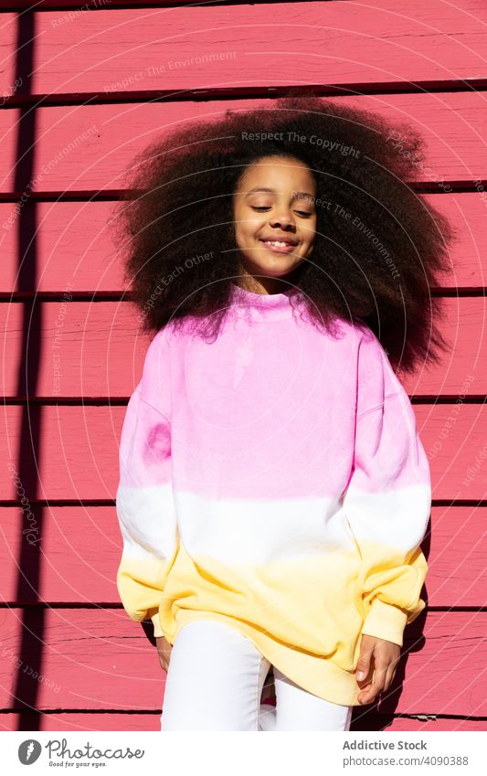 Smiling girl standing near pink wall smiling trendy african american happy beautiful pretty cheerful attractive cute people happiness joy brunette sweatshirt