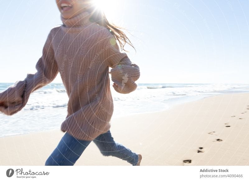 crop girl running on beach sea waves barefoot footprints sunny daytime freedom carefree lifestyle leisure kid child teen water ocean energy activity sky