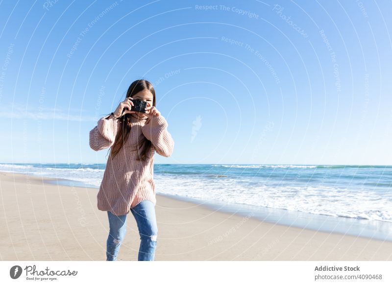 Smiling girl taking photos on beach photo camera sea sunny daytime smiling sand cloudless sky lifestyle leisure hobby kid child teen happy weekend technology