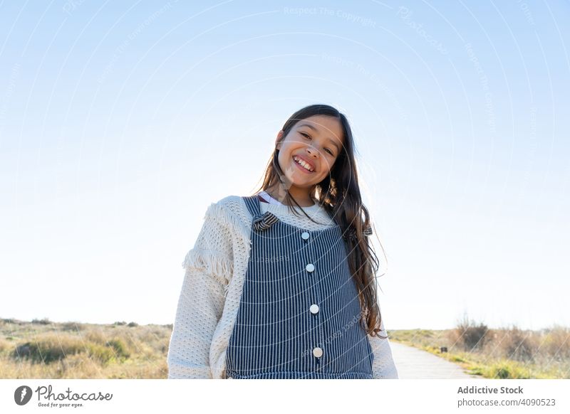 Smiling girl looking at camera on path beach cheerful sky cloudless sunny bright daytime countryside kid child teen weather clear happy joy smiling long hair