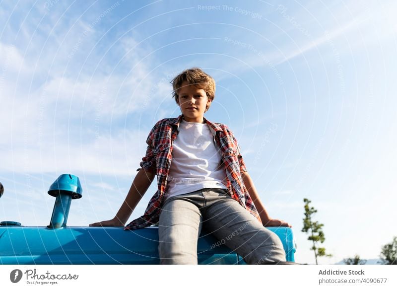 Boy sitting on tractor on farm boy field agriculture sky clouds sunny daytime teen kid child casual lifestyle leisure relax rest rural summer ranch rustic