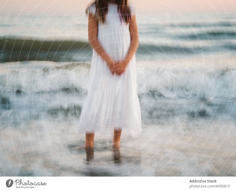 blur girl standing on seaside among waves portrait smiling charming water beach adorable summer beautiful female kid child childhood preschooler innocence