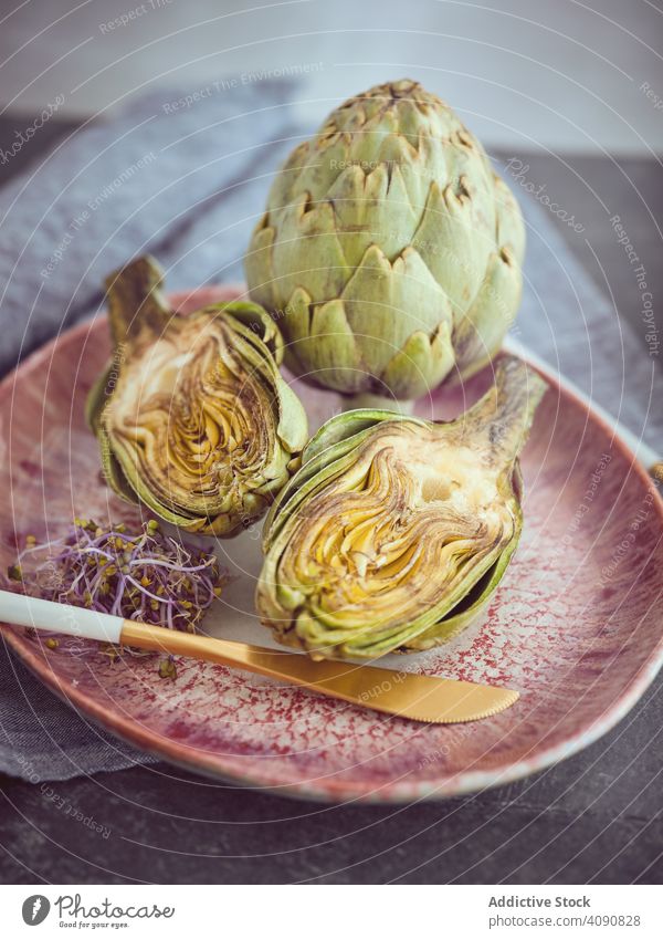 Knife and artichokes on plate knife cut whole table food cooking organic healthy fresh diet nutrition vegan vegetarian ingredient natural napkin raw halves