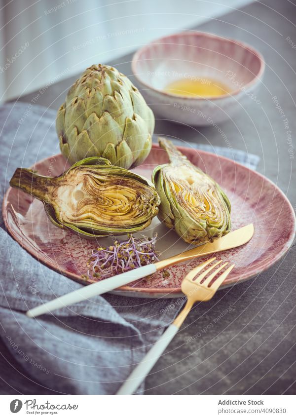 Knife fork and artichokes on plate knife cut whole table food cooking organic healthy fresh diet nutrition vegan vegetarian ingredient natural napkin raw halves