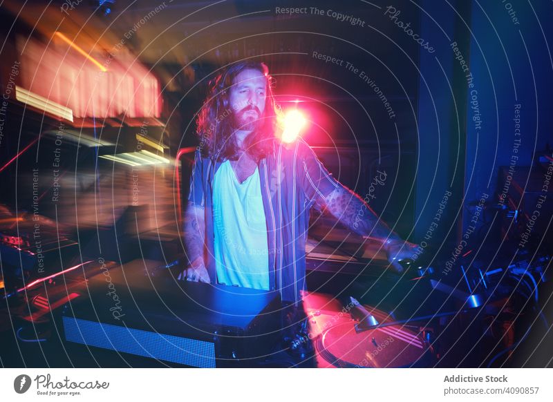 Bearded Dj man playing disco music in a club electronics discotheque crowd volume professional audio show mixer stereo sounds part headphone panel instrument dj