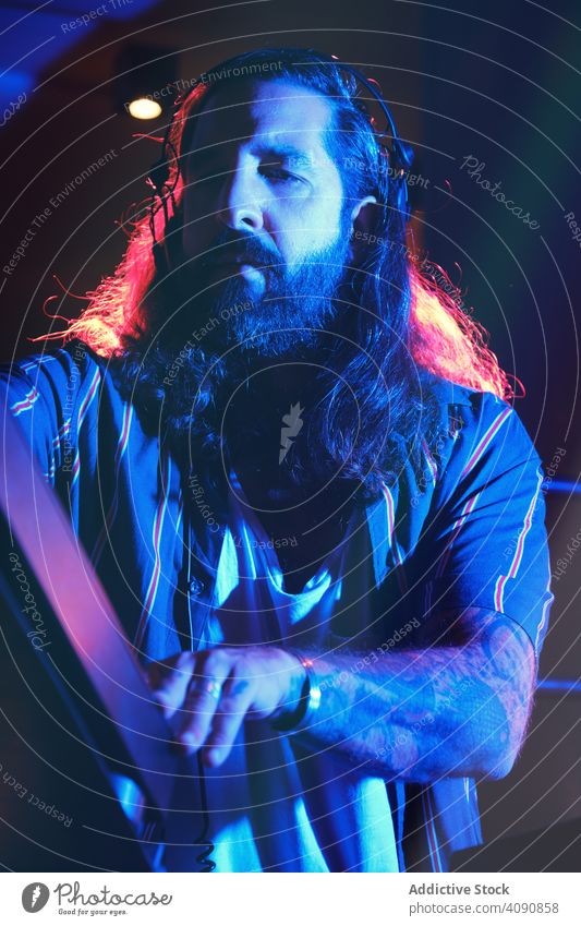 Bearded Dj man playing disco music in a club electronics discotheque crowd volume professional audio show mixer stereo sounds part headphone panel instrument dj