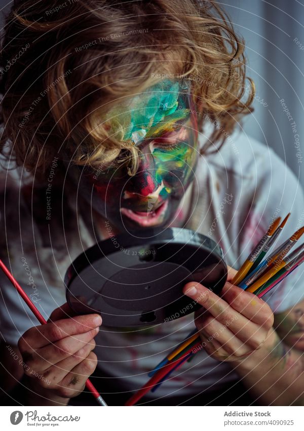 Pretty boy smeared in paints drawing on face painted painting fun playful mirror child kid creative funny dirty cute pretty adorable cool blond casual playing