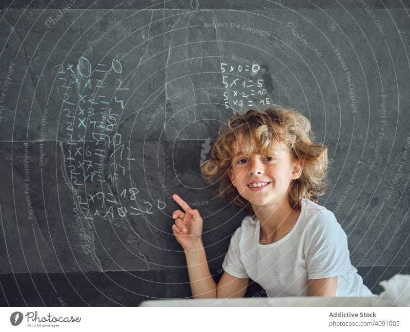 Child showing on multiplication table on wall child smiling education study kid learn mathematics elementary knowledge write lesson chalk childhood teach number