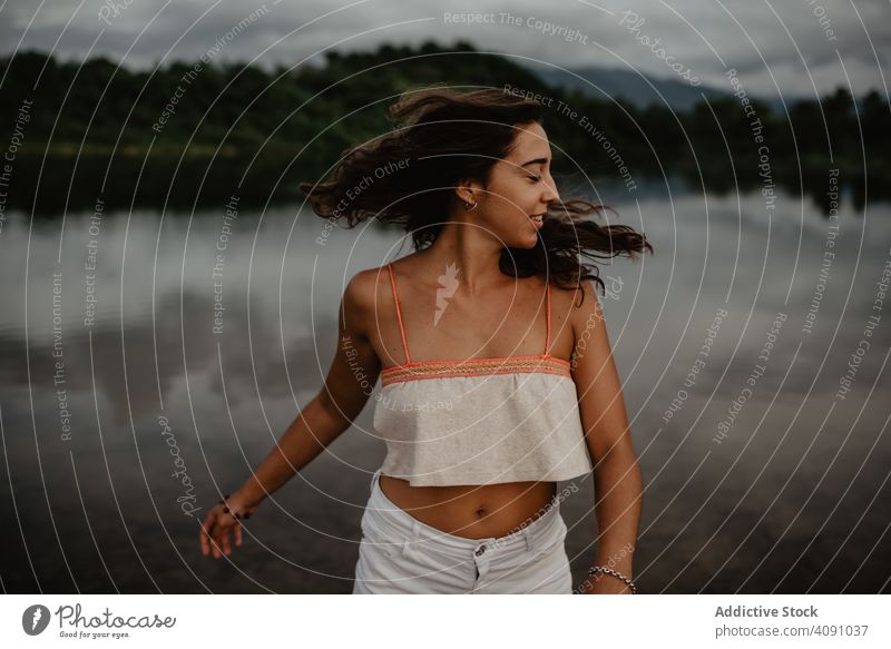 Cheerful woman dancing near lake smiling closed eyes hands up excited young nature water female calm tranquil cheerful happy joy activity raised lady lifestyle