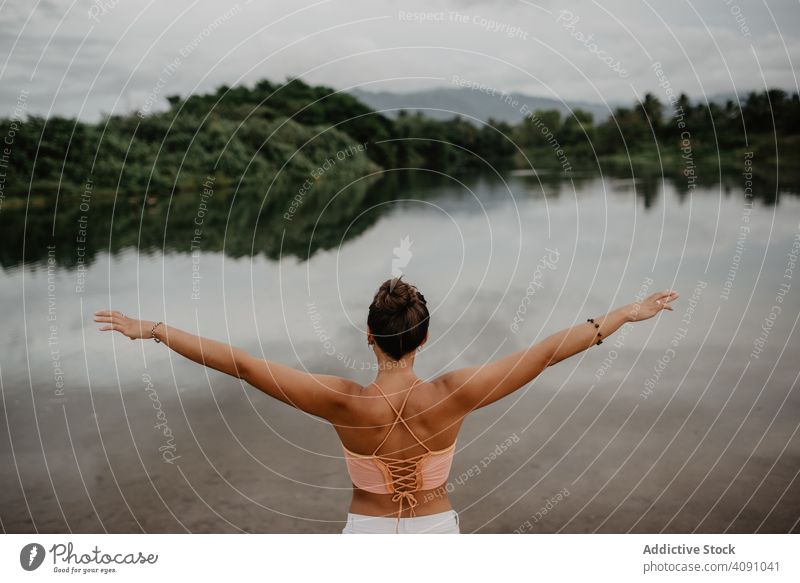 Unrecognizable woman enjoying freedom near lake outstretched arms young countryside nature lifestyle leisure female gesture pond calm tranquil serene peaceful