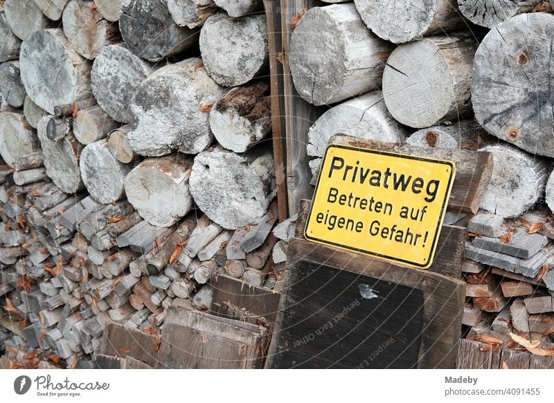 Yellow tin sign warning of stacked firewood in front of an old farmhouse in autumn in Rudersau near Rottenbuch in the district of Weilheim-Schongau in Upper Bavaria