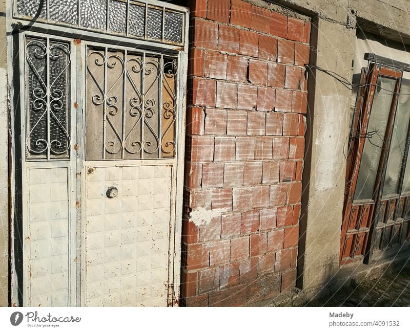 Old empty workshop with door made of wrought iron and unplastered brick in the sunshine in Alacati near Cesme at the Mediterranean Sea in the province of Izmir in Turkey