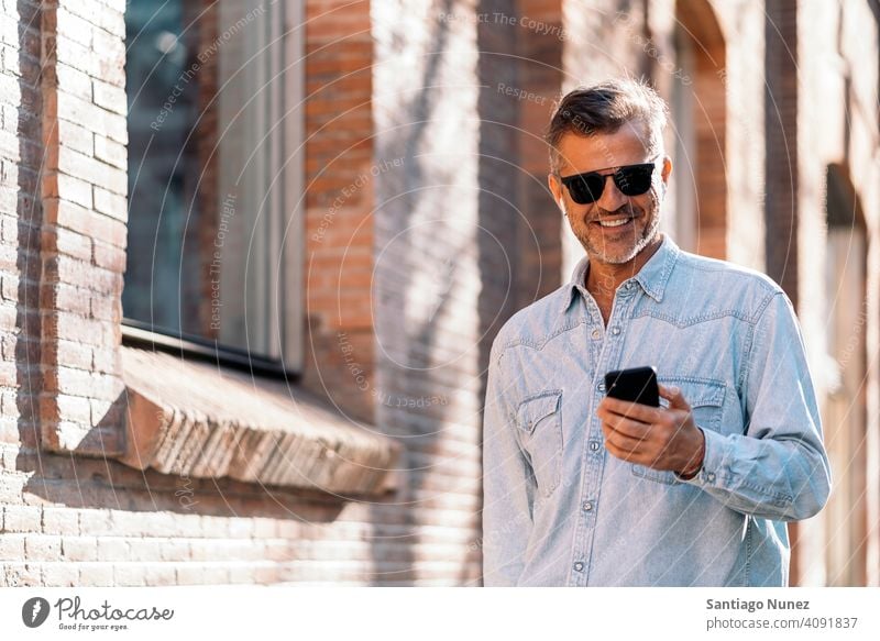 Business man using his smartphone in the street. person lifestyle people middle aged handsome senior outdoors caucasian city adult male portrait casual urban