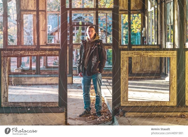 portrait of a smiling young man standing in a ruin house positive smile powerful sunlight evening jacket hoodie beautiful handsome attractive frame construction
