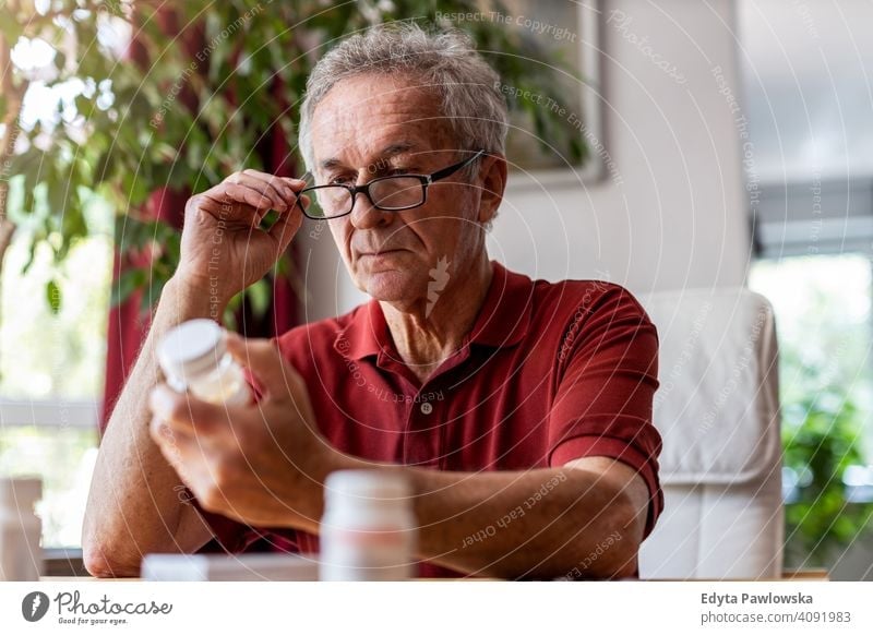 Senior man taking prescription medicine at home senior elderly grandfather old pensioner retired retirement aged mature house male people lifestyle