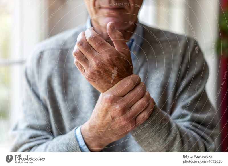 Senior man with arthritis rubbing hands rheumatism stiff joints massaging wrist osteoporosis touching injury cramp senior elderly grandfather old pensioner