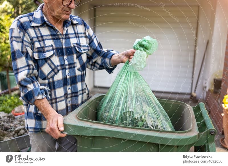 Senior man taking out garbage senior elderly grandfather old pensioner retired retirement aged mature home house male people lifestyle domestic life real people