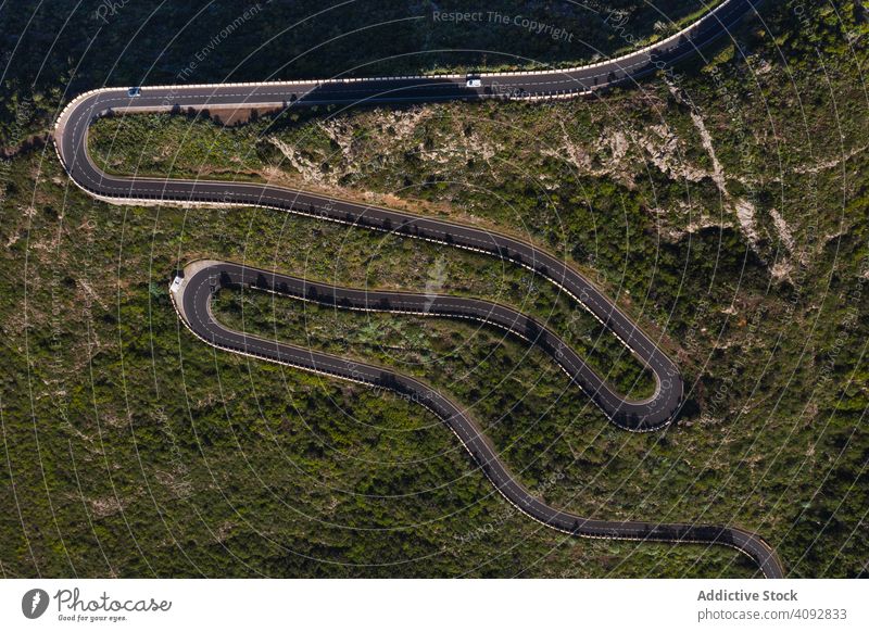 Curving road through desert landscape curving drone view empty aerial winding remote country green tenerife spain countryside sunny light travel trip weaving