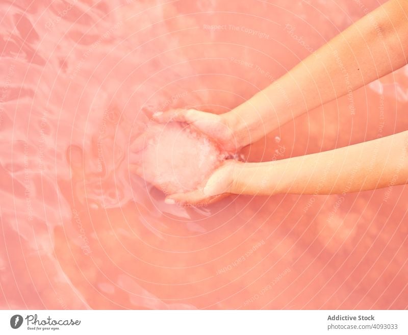 Female holding healing salt pile in pink water woman lake sea natural exotic red lagoon handful leisure heap therapeutic female beach holiday ocean travel