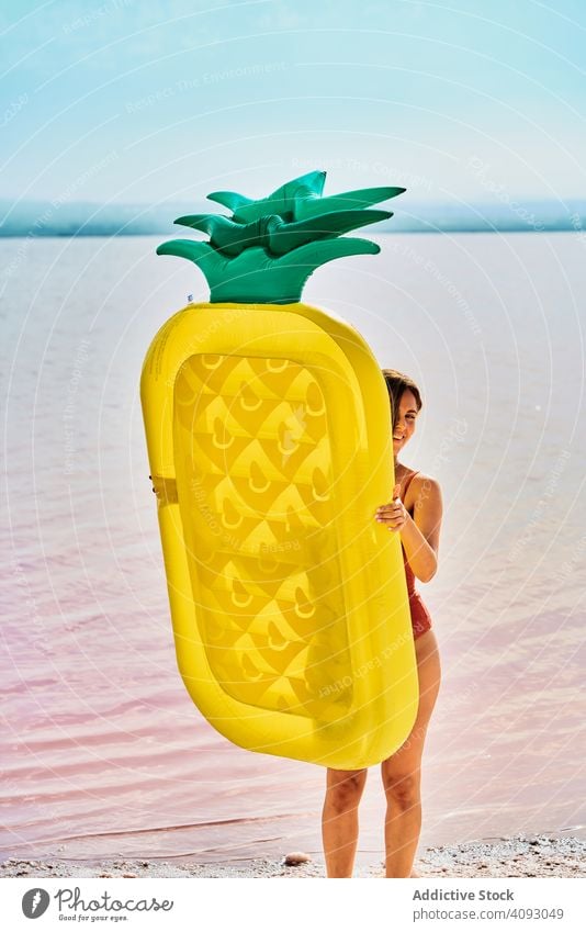 Female with inflatable mattress on coast in summer woman air covered tan shape body seashore pineapple vivid form vibrant red lagoon female walk water beach