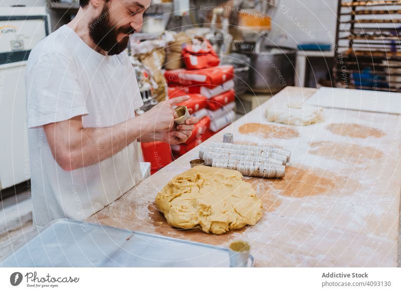 Bearded confectioner putting dough into cup bakery table kitchen pastry preparation fresh man raw cuisine professional food chef restaurant cafe cook recipe
