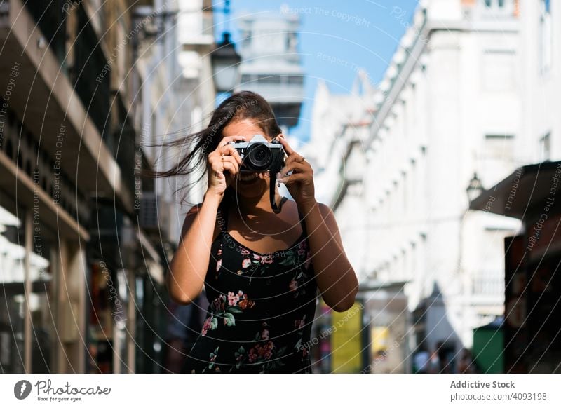 Casual woman taking photo with camera while standing on street town travel casual confident picture scenic lisbon portugal sunny city photographer young adult