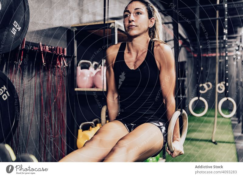 Hardworking female training on gymnastic rings woman pull-ups sport club hardworking focused shapely workout fit fitness active exercise athlete equipment
